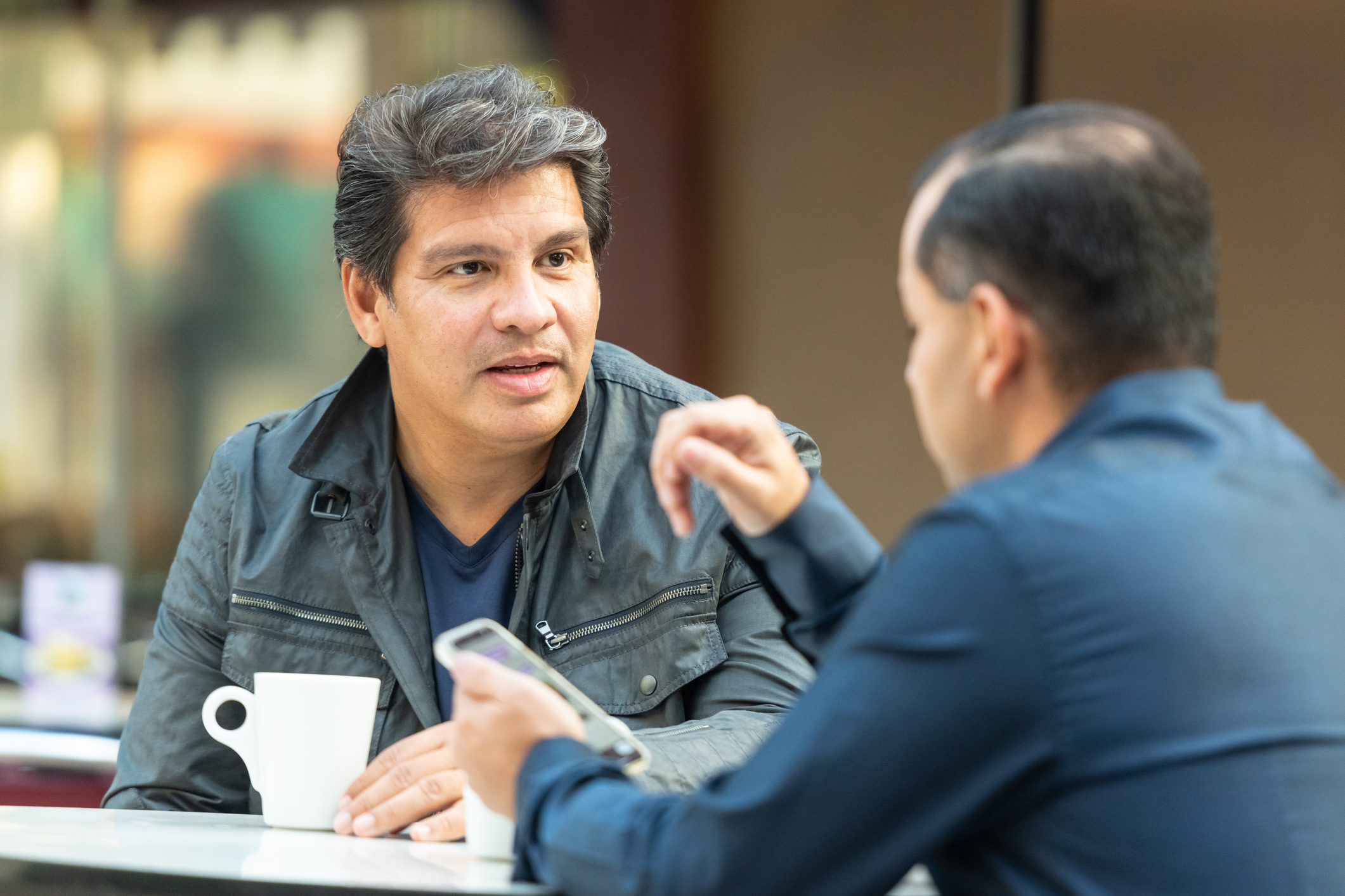 two men talking over coffee at a table